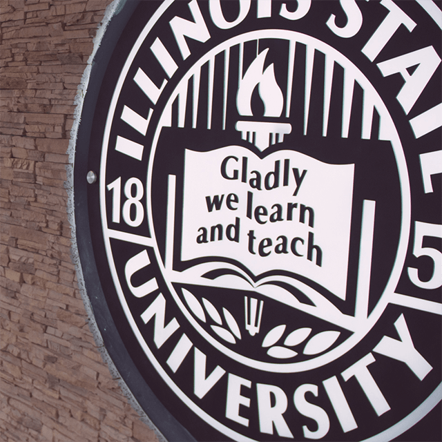 Illinois State University emblem on a brick wall indoors.